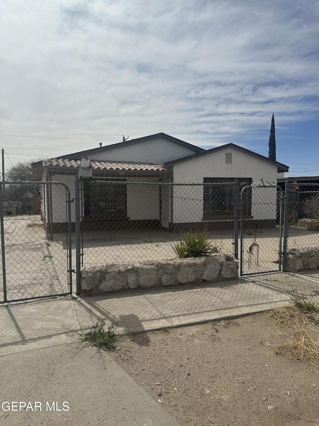 manufactured / mobile home with a fenced front yard, stucco siding, a tile roof, and a gate