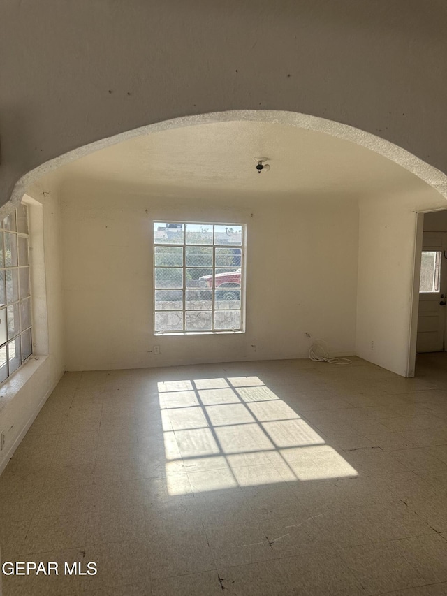 unfurnished room featuring arched walkways