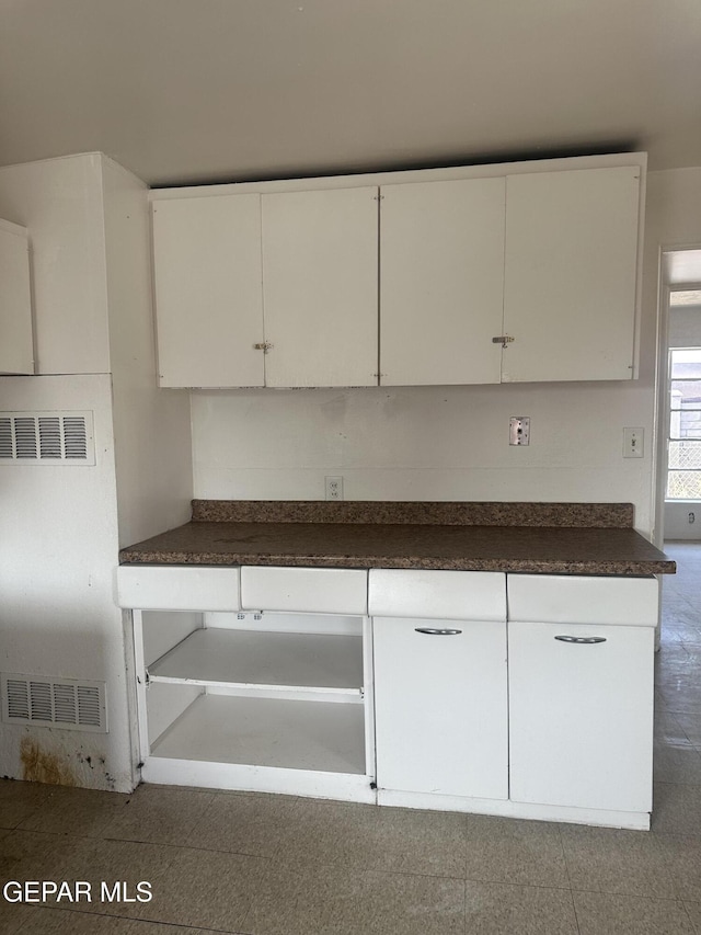 kitchen featuring dark countertops, visible vents, and white cabinets