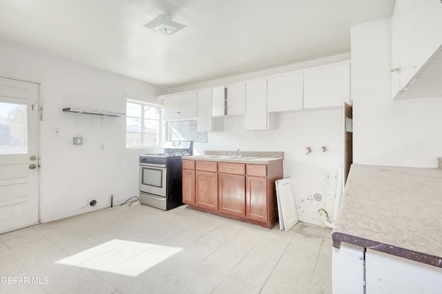 5930 Cleveland Ave, El Paso, TX 79905 - kitchen with brown cabinets, light tile patterned floors, gas range, and a sink