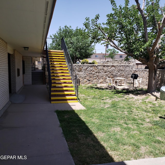 view of yard featuring a patio area, stairs, and fence