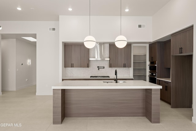 kitchen featuring visible vents, a sink, light countertops, wall chimney exhaust hood, and modern cabinets