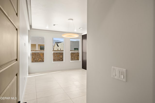 hallway with light tile patterned flooring, visible vents, and baseboards