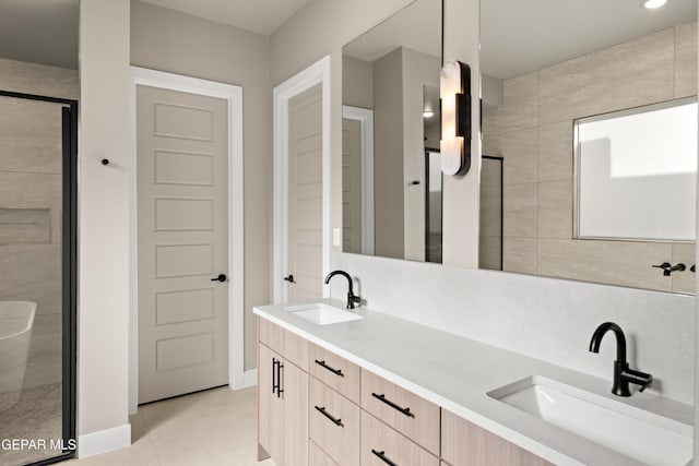 full bathroom featuring double vanity, a shower stall, baseboards, and a sink