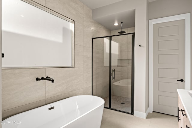 bathroom with vanity, a freestanding tub, a stall shower, tile patterned flooring, and tile walls