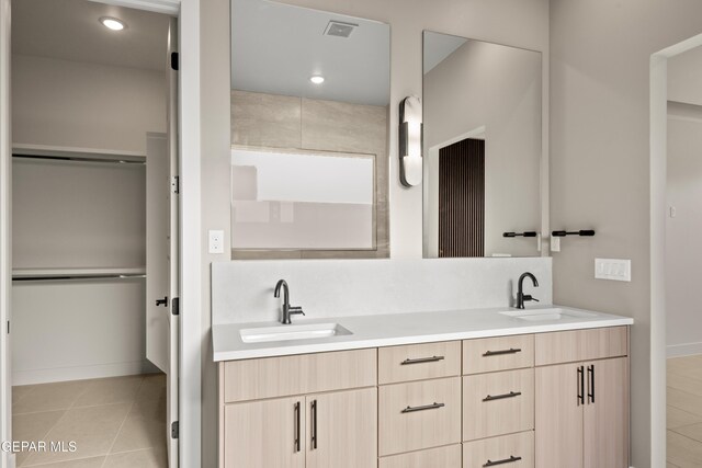 bathroom featuring a sink, visible vents, double vanity, and tile patterned flooring