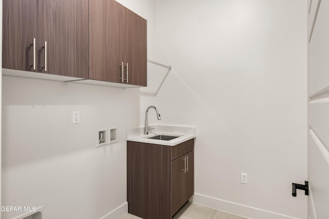 washroom with a sink, cabinet space, light tile patterned floors, baseboards, and hookup for a washing machine