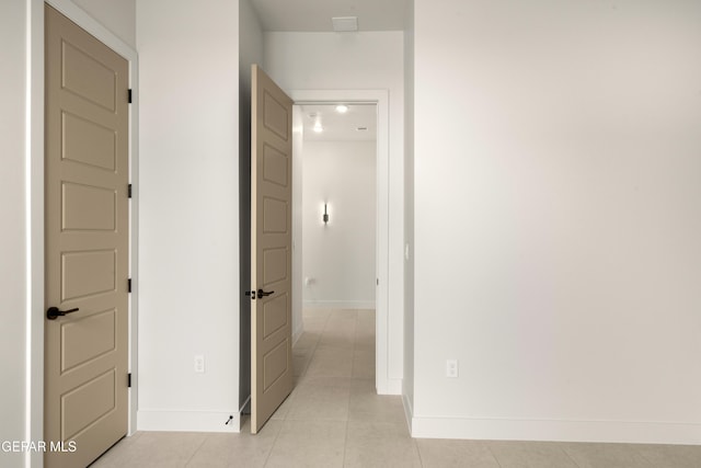 hallway featuring light tile patterned flooring and baseboards