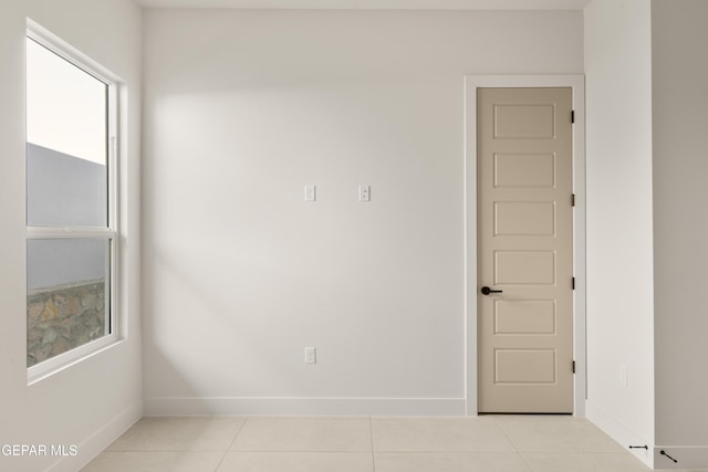 unfurnished room with light tile patterned floors and baseboards