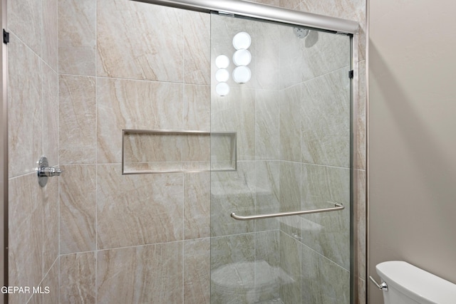 bathroom featuring toilet and a shower stall