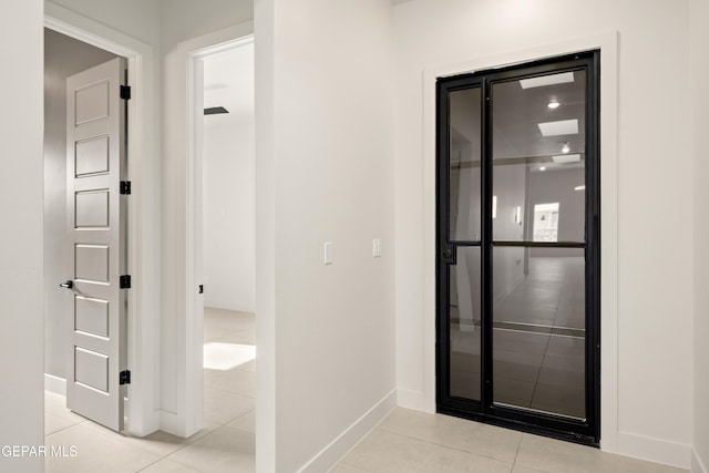 hall featuring light tile patterned floors and baseboards