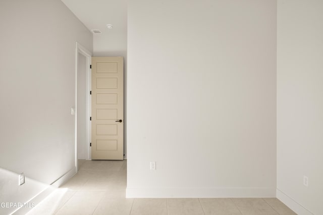 empty room featuring light tile patterned flooring, visible vents, and baseboards