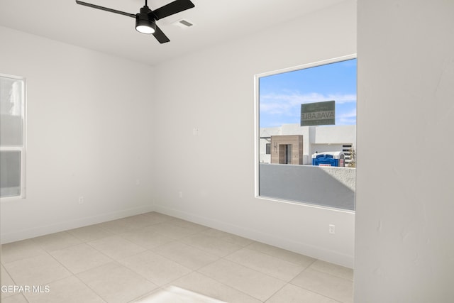 tiled empty room with visible vents, baseboards, and a ceiling fan