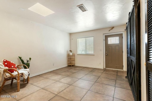 foyer featuring a skylight, light tile patterned floors, baseboards, and visible vents