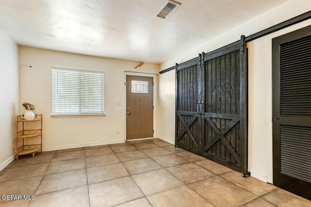 entryway featuring tile patterned floors, a barn door, baseboards, and visible vents