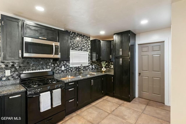 kitchen featuring stainless steel microwave, dark cabinets, black gas range, and a sink