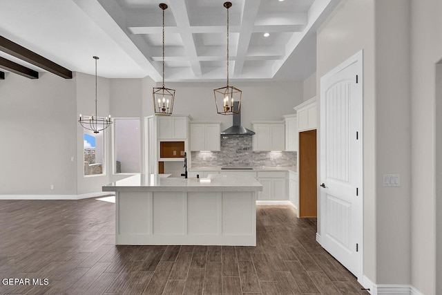 kitchen with cooktop, light countertops, a towering ceiling, wall chimney exhaust hood, and backsplash