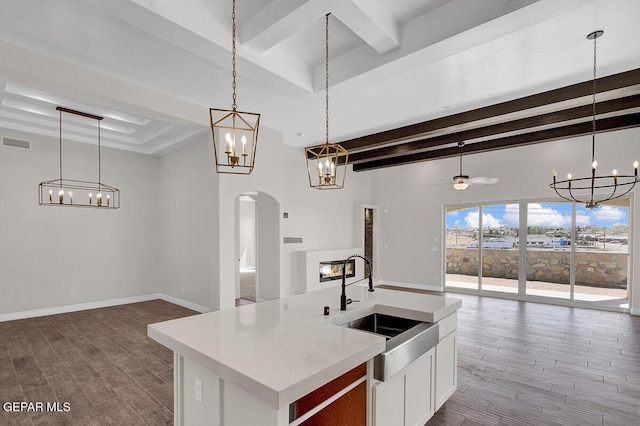 kitchen with visible vents, wood tiled floor, open floor plan, light countertops, and a sink