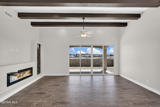 unfurnished living room featuring a ceiling fan, baseboards, dark wood-type flooring, a glass covered fireplace, and beamed ceiling