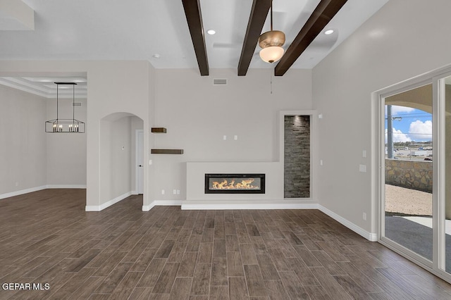 unfurnished living room featuring a glass covered fireplace, beam ceiling, visible vents, and dark wood-style flooring