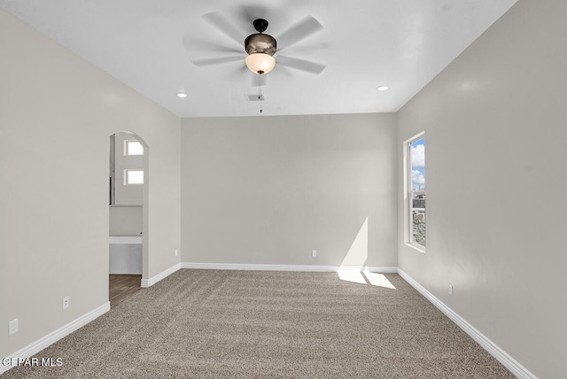 carpeted spare room with recessed lighting, baseboards, arched walkways, and a ceiling fan