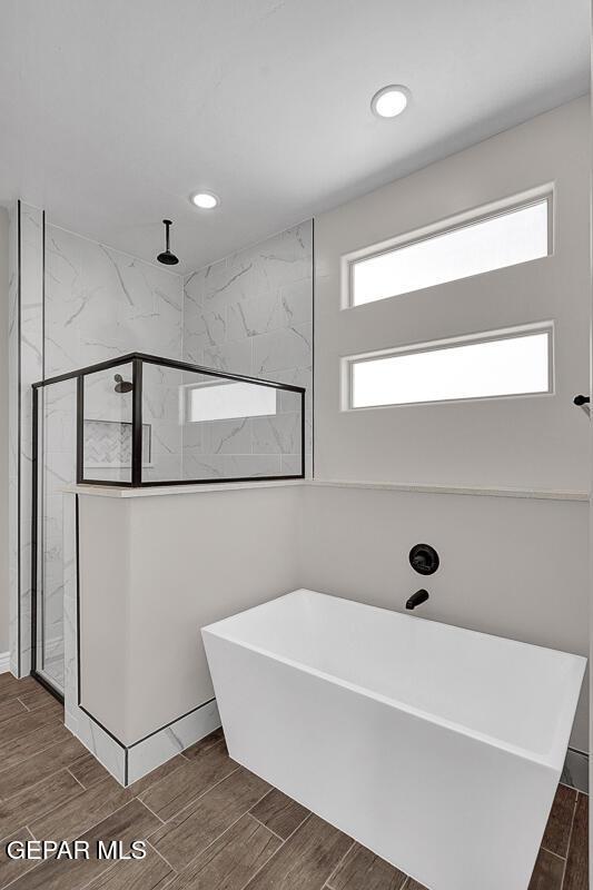 full bath featuring a marble finish shower, a soaking tub, and wood tiled floor