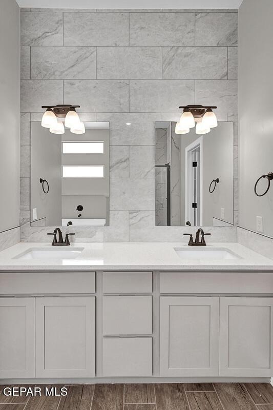 full bath featuring double vanity, wood finish floors, and a sink