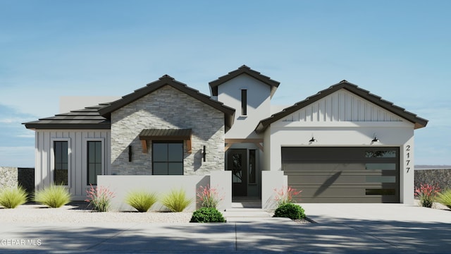 view of front of property featuring stone siding, an attached garage, board and batten siding, and driveway