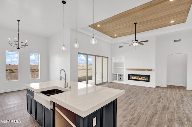 kitchen with wood ceiling, light wood-style floors, a tray ceiling, and dark cabinets