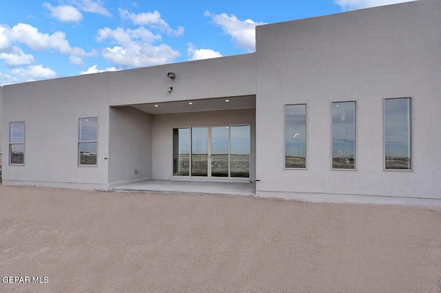 rear view of house with a patio area and stucco siding