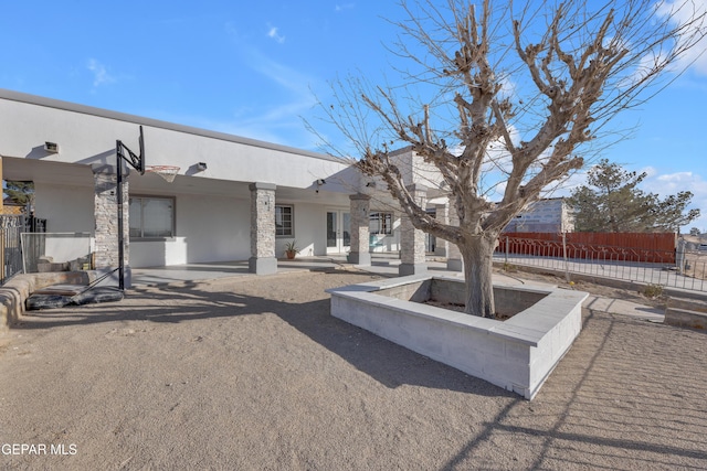 rear view of house featuring stucco siding, french doors, an outdoor fire pit, and fence