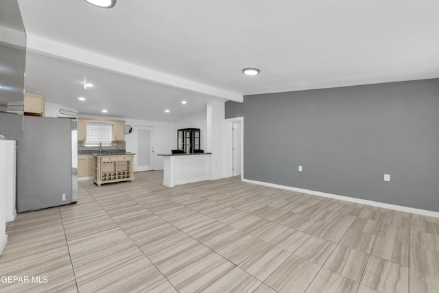 unfurnished living room with lofted ceiling with beams, baseboards, recessed lighting, and a sink