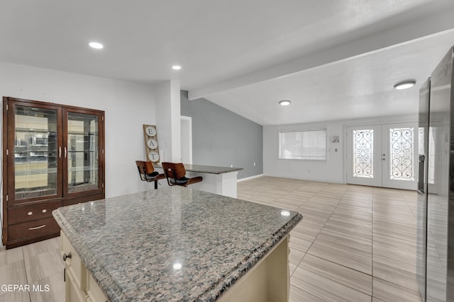 kitchen with dark stone countertops, lofted ceiling with beams, french doors, open floor plan, and a center island