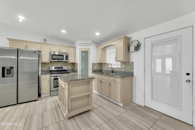 kitchen featuring backsplash, dark stone countertops, cream cabinetry, stainless steel appliances, and a sink