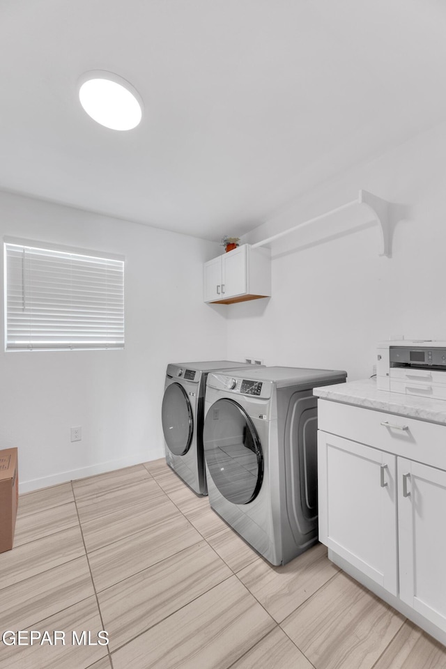 washroom featuring cabinet space and washer and clothes dryer