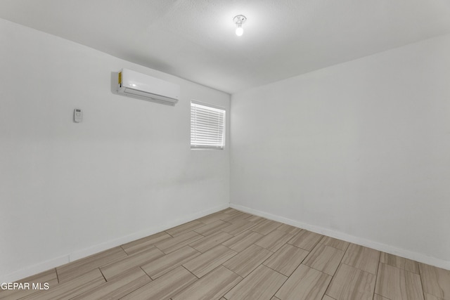 unfurnished room featuring an AC wall unit and baseboards