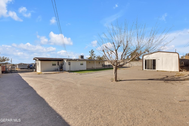 rear view of house featuring an outbuilding and fence