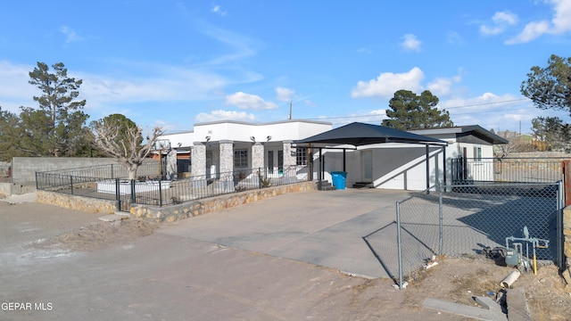 view of front of house with an attached carport, concrete driveway, and fence