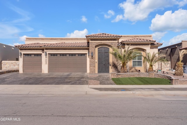 mediterranean / spanish house with a tiled roof, stucco siding, an attached garage, and driveway