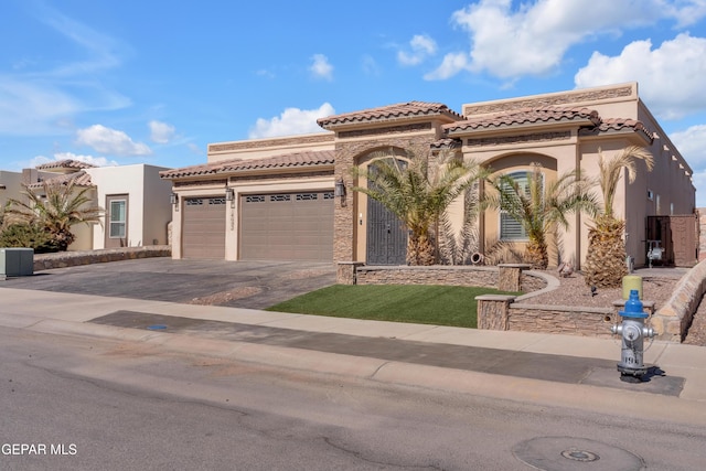 view of front of home with stucco siding, driveway, a tile roof, and a garage