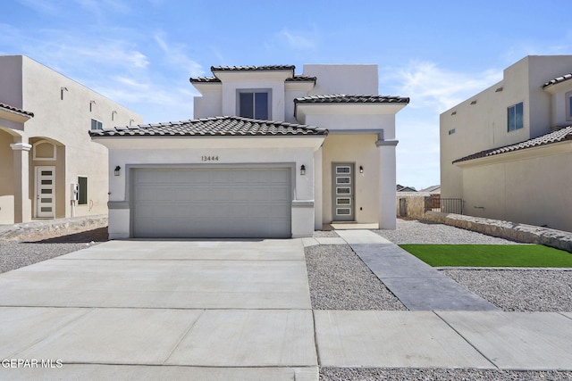 view of front facade with concrete driveway, an attached garage, a tile roof, and stucco siding