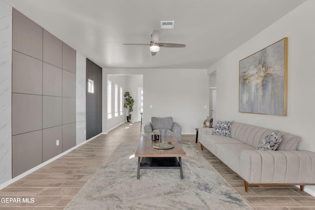 living room with baseboards, a ceiling fan, visible vents, and wood tiled floor