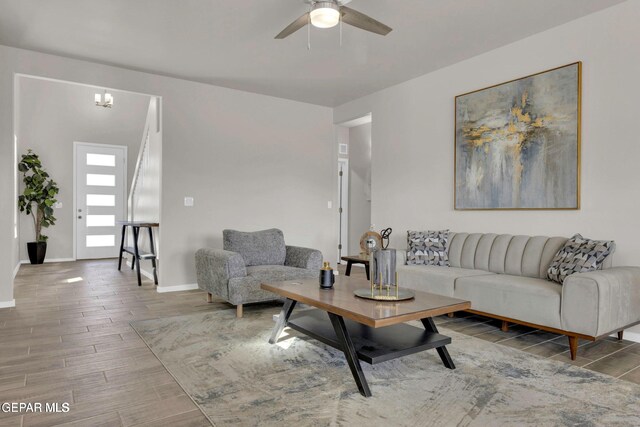 living area with ceiling fan with notable chandelier, baseboards, and wood tiled floor