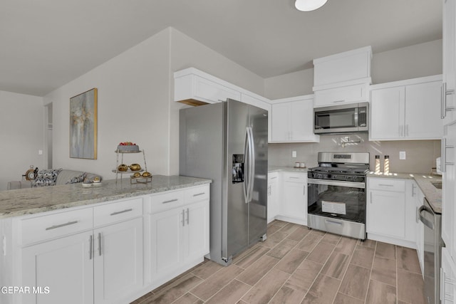 kitchen featuring white cabinets, backsplash, appliances with stainless steel finishes, and light stone counters