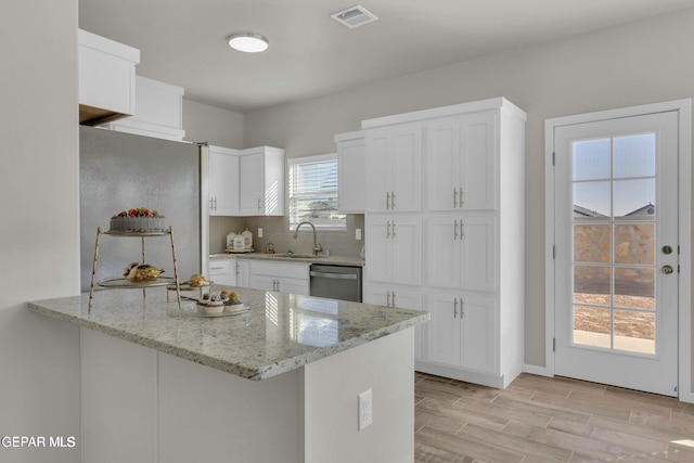 kitchen with visible vents, a peninsula, stainless steel appliances, white cabinetry, and a sink