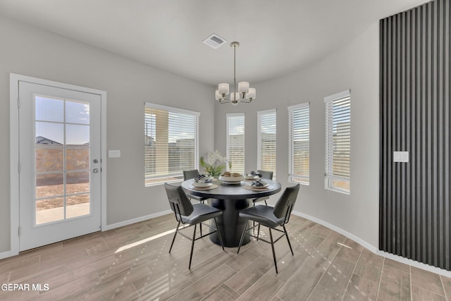 dining room with a wealth of natural light, visible vents, wood finish floors, and a chandelier