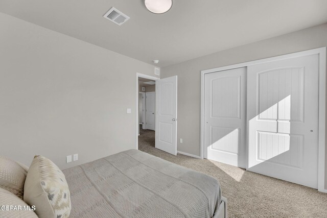 carpeted bedroom featuring visible vents and a closet