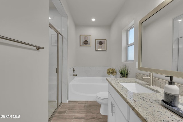 bathroom with vanity, a shower stall, a garden tub, and toilet