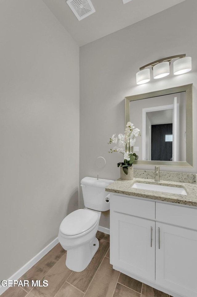 bathroom featuring visible vents, toilet, vanity, and wood tiled floor