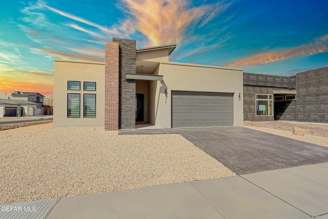 modern home with stucco siding, an attached garage, and aphalt driveway